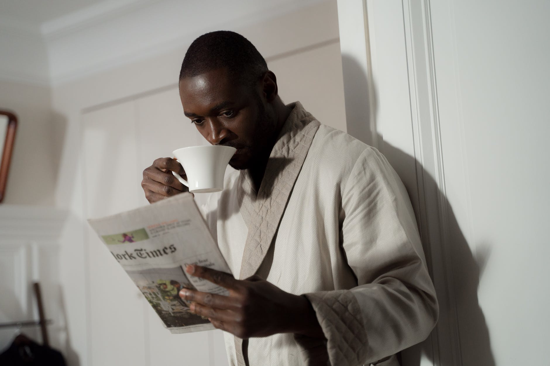 a man reading the newspaper while drinking coffee
